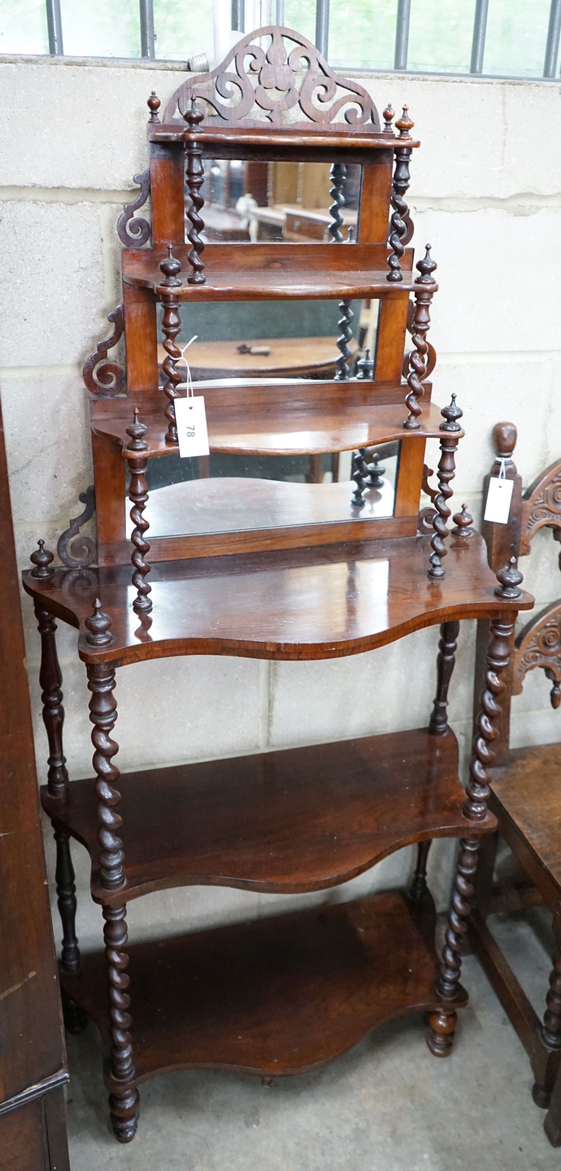 A late Victorian rosewood serpentine front six tier whatnot with mirror and barley twist support to shelves